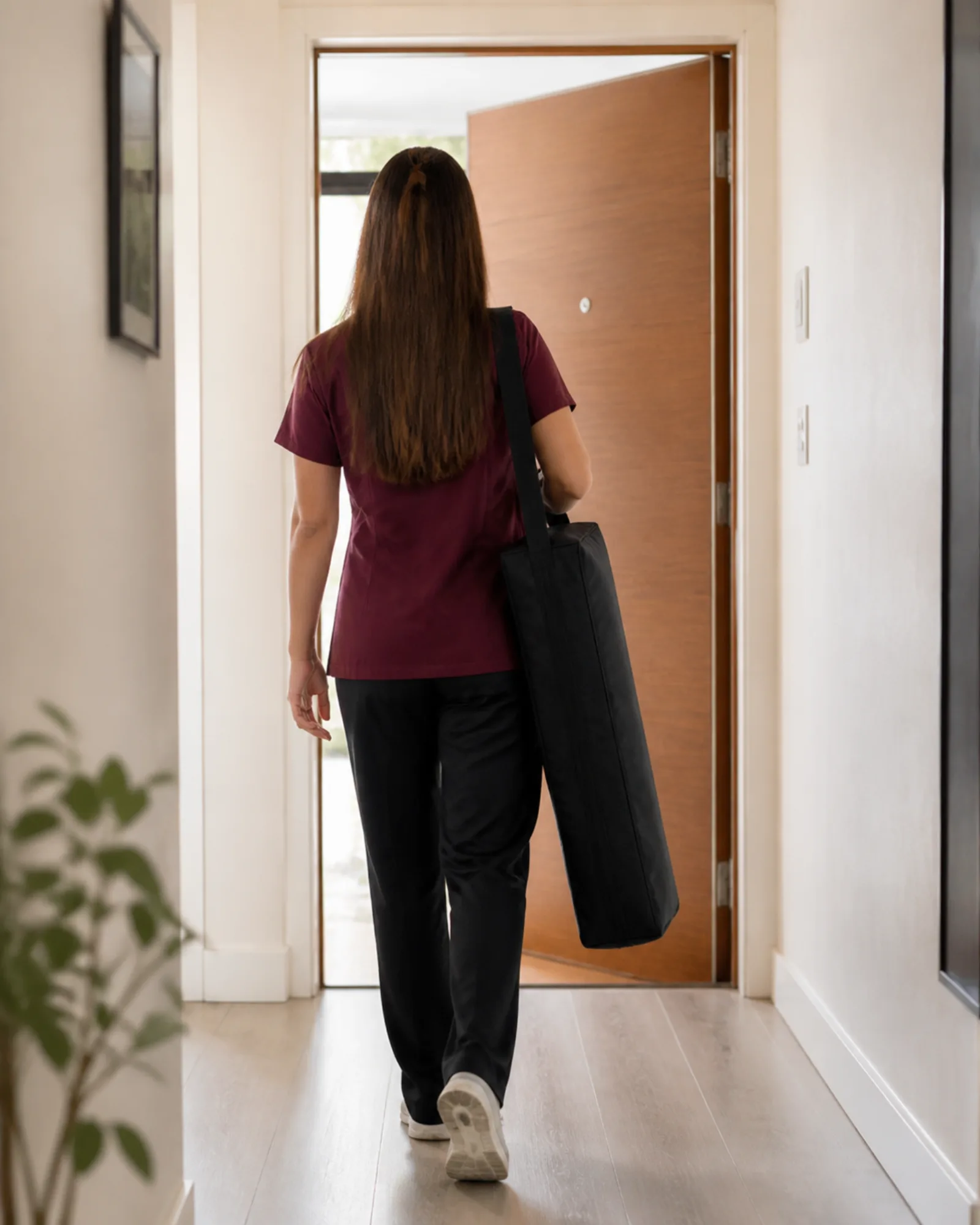 Physiotherapist carrying a folded treatment table to an apartment door